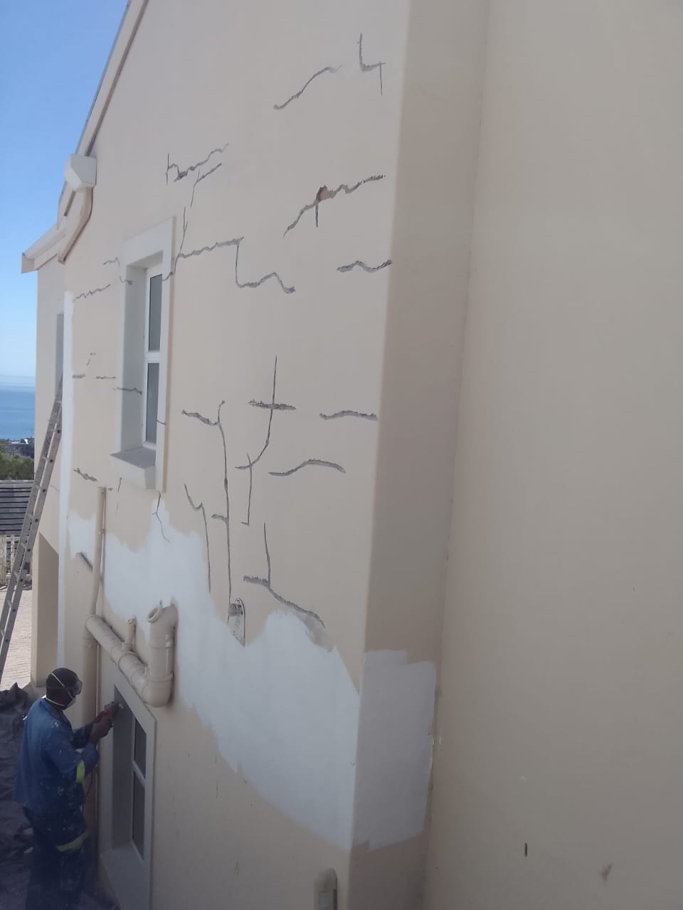 An exterior wall covered in cracks all raked out and marked, ready for filling