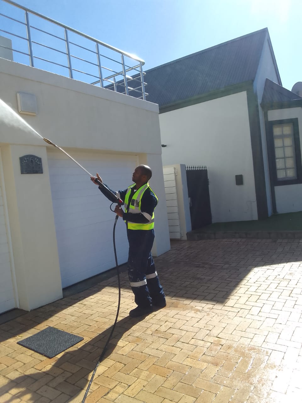 Worker high-pressure washing an exterior wall as preparation before painting